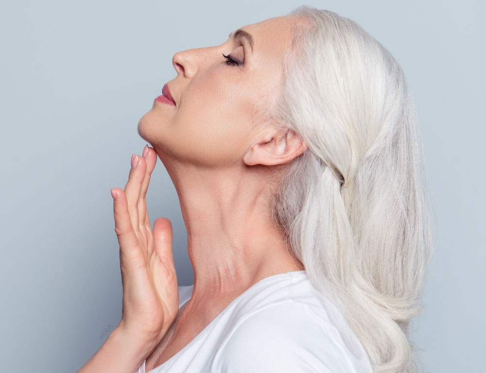 Profile shot of a older woman examining her chin and lifting her head up