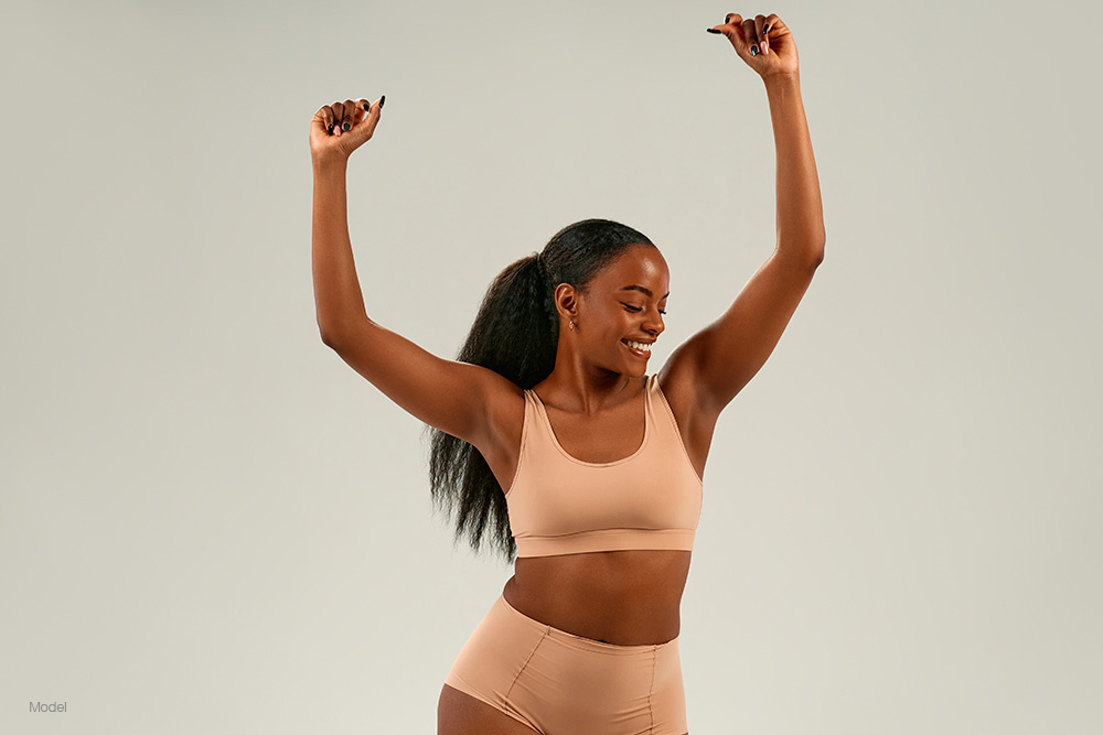 woman in tan underwear with her arms raised