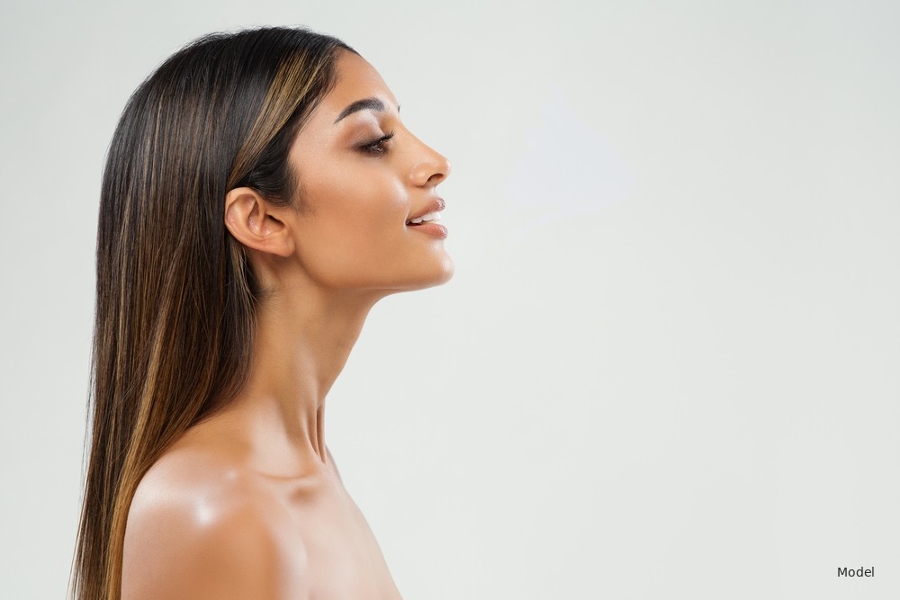 Young woman in side profile with a refined nose against a soft light background